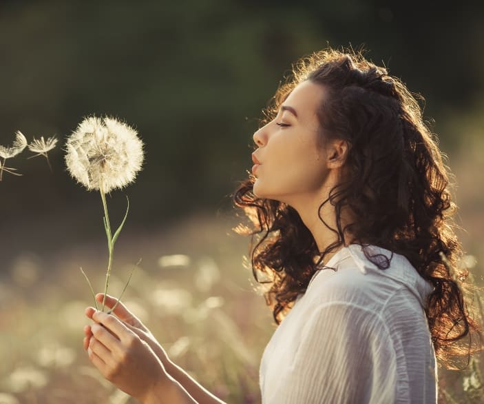 Imagen de una mujer soplando una planta