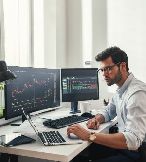 Imagen de un hombre trabajando con varios equipos portátiles 