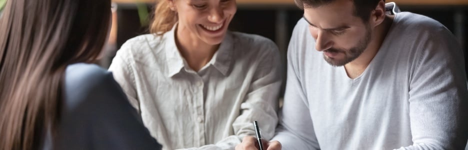 Imagen de una pareja milenaria emocionada reunida con una agente inmobiliaria o corredora en un café que firma un contrato comprando la primera propiedad juntos, los cónyuges felices firman el acuerdo de cierre con el banquero para tomar un préstamo