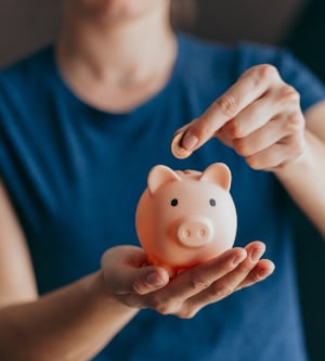Imagen de una mujer ahorrando, metiendo monedas en su hucha