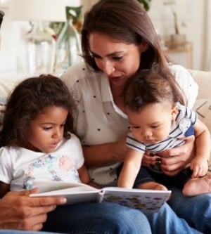 Imagen de unos padres leyendo un cuento a sus hijos