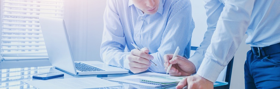 Imagen de dos personas repasando números sobre un papel