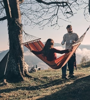 Imagen de hermosa joven manteniendo los brazos extendidos mientras se relaja en una hamaca al aire libre