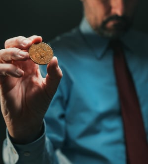 Imagen de un hombre con una moneda Bitcoin en su mano