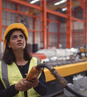 Imagen de Trabajadora de almacén encargada de utilizar una grúa para levantar rollos de láminas metálicas en el almacén para importar cintas para fabricación de láminas metálicas.