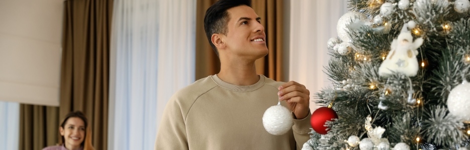 Imagen de un hombre decorando su arbol de Navidad