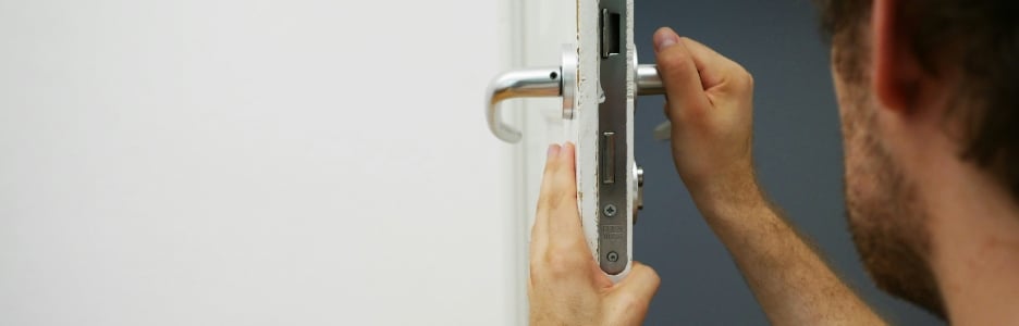 Imagen de un hombre cambiando la cerradura de una puerta de su casa