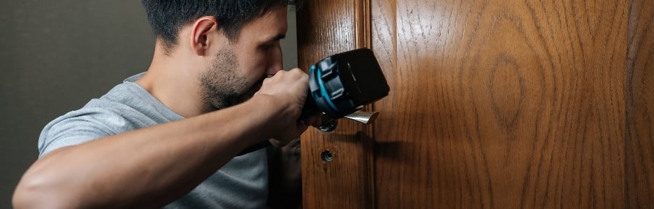 Imagen de un hombre arreglando la cerradura de una puerta de una casa