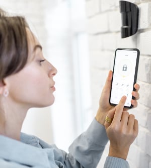 Imagen de una mujer encendiendo su alarma con una aplicación en su teléfono móvil