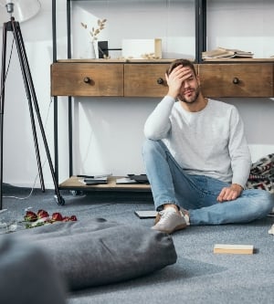 Imagen de un hombre en el salón de su casa frustrado por un robo en su vivienda