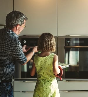 Imagen de niña con su abuelo mirando las galletas de la hornada