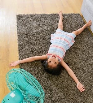 Imagen de un adolescente refrescando con un ventilador en casa