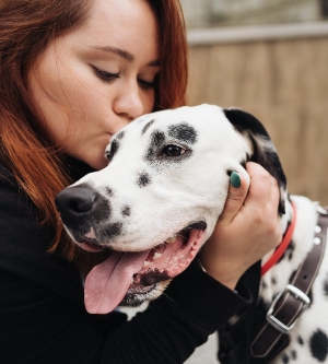 Imagen de una mujer feliz besando a su perro dálmata durante un paseo urbano por la ciudad. Concepto de amistad, amor y cuidado.