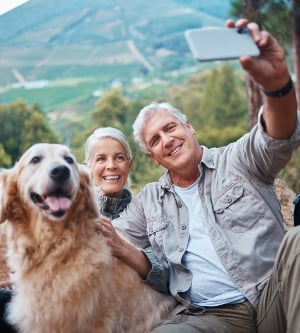 Imagen de un perro y dos adultos haciendo un selfie todos juntos