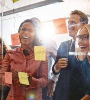 Imagen de un grupo de empleados pegando notas en la pared de cristal