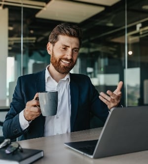 Imagen de un hombre de negocios caucásico positivo con traje sentado en la oficina hablando con socios comerciales a través de una computadora portátil