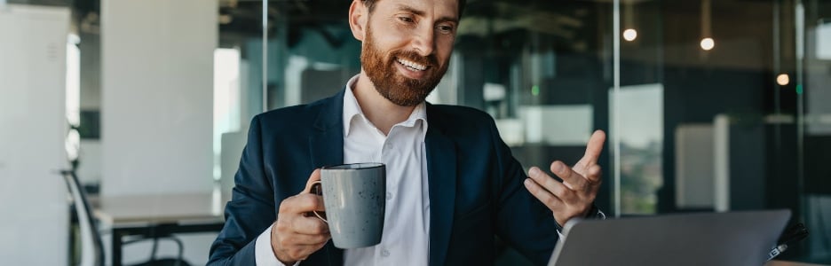 Imagen de un hombre de negocios caucásico positivo con traje sentado en la oficina hablando con socios comerciales a través de una computadora portátil