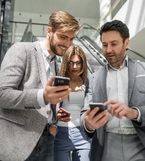 Imagen de un grupo de jóvenes empresarios mirando las pantallas de sus teléfonos inteligentes