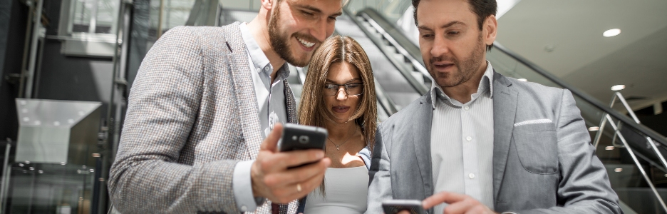 Imagen de un grupo de jóvenes empresarios mirando las pantallas de sus teléfonos inteligentes