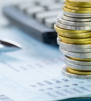 Imagen de monedas sobre unos cálculos en una hoja