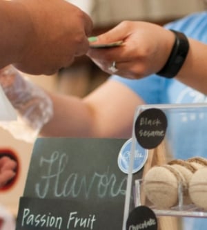 Imagen de una vendedora de macarons francés atendiendo a un cliente