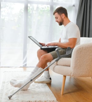 Imagen de una persona en muletas sentado en el sillón