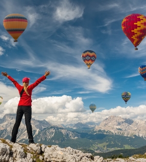 Imagen de una persona saludando a los globos aerostáticos en la montaña
