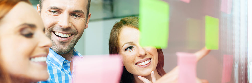 Imagen de un grupo de empleados pegando stickies a una pared de cristal