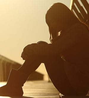 Imagen de una mujer sentada sobre un puente llorando