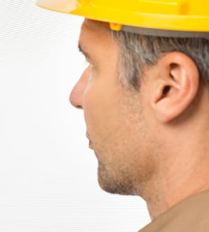 Imagen de un hombre con un casco de seguridad de color amarillo buscando plagas en la cocina