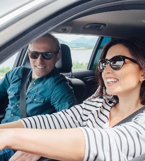 Imagen de una mujer conduciendo su coche mientras el pasajero habla con ella