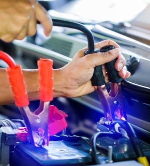 Imagen de un hombre arrancando su coche con pinzas