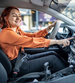 Imagen de una mujer sonriente poniendo la radio en su coche