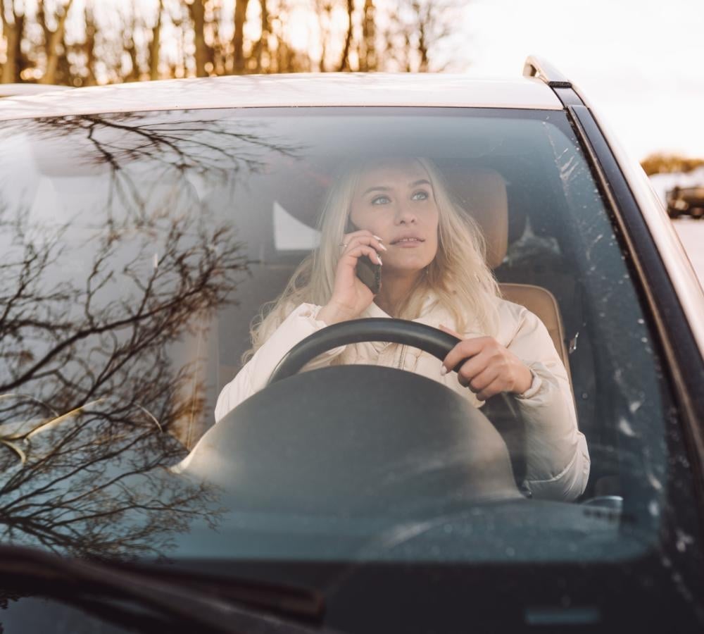 Imagen de una mujer conduciendo su coche sospechando la presencia del uso de drones de la DGT