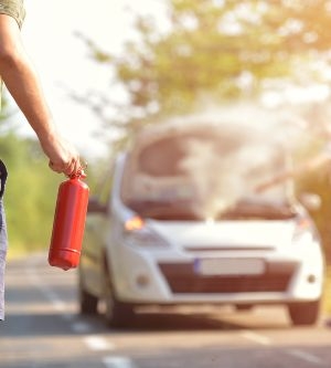 Imagen de una persona utilizando un extintor para apagar las llamas de su coche