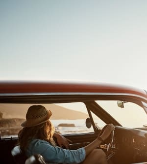 Imagen de una joven disfrutando de un viaje por carretera a lo largo de la costa.