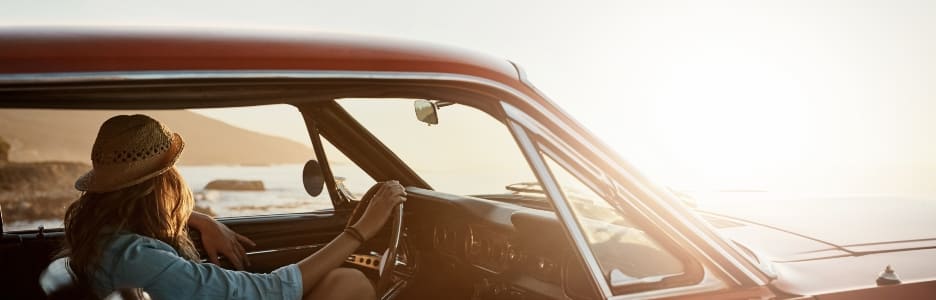 Imagen de una joven disfrutando de un viaje por carretera a lo largo de la costa.