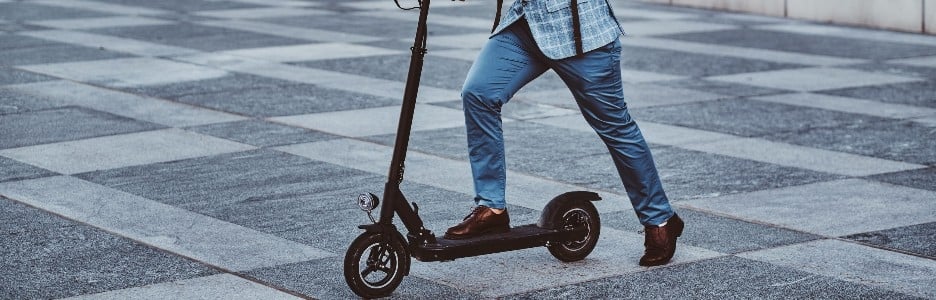 Imagen de un hombre moderno y alegre está conduciendo su scooter eléctrico cerca de su oficina después de un largo y duro día