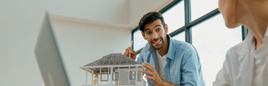 Imagen de un hombre enseñando modelo de una vivienda sostenible 