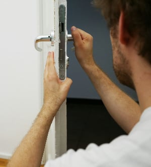 Imagen de un hombre cambiando la cerradura de una puerta de su casa