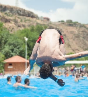 Imagen de un hombre saltando en el agua de la piscina