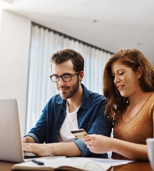 Imagen de ella conoce todos los mejores sitios web con grandes ofertas especiales. Una pareja joven hace algunas compras en línea en una computadora portátil juntos durante el fin de semana en casa