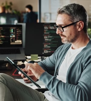 Imagen de un programador, empresario y gerente investigando en una tablet sobre desarrollo de software, desplazamiento o actualización de código en línea, tecnología digital, e ingeniero experimentado diseñando la interfaz de usuario (UI) de un sitio web y una aplicación en una startup creativa