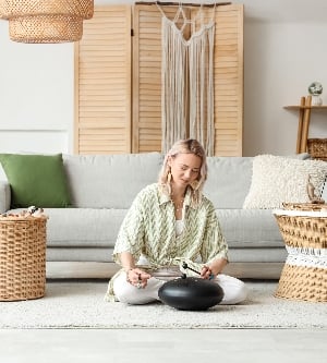 Imagen de una mujer tocando glucófono y meditando en casa