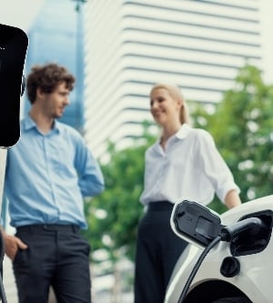 Imagen de enfoque el estacionamiento: automóvil eléctrico conectado a la estación de carga pública con desenfoque progresivo de empresarios tomando café, fondo de apartamento y condominio de edificio residencial para un concepto ecológico.