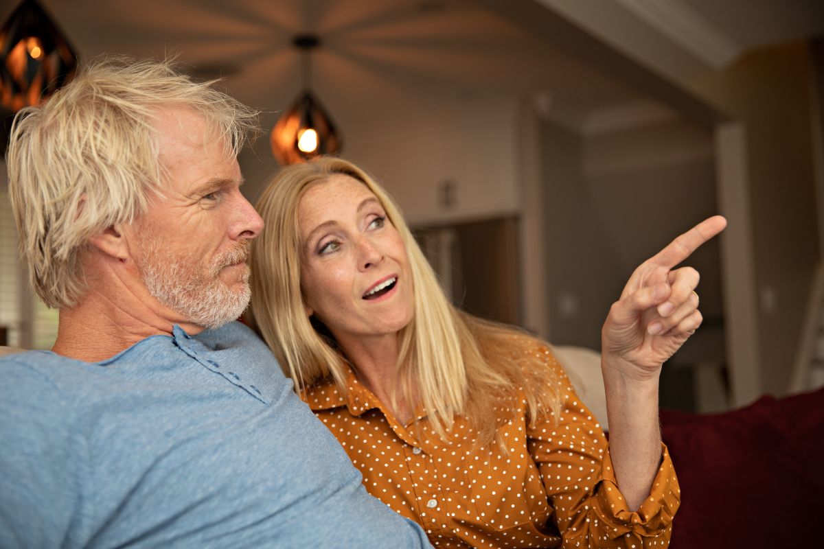Image of a woman with her partner, pointing something out on the TV screen