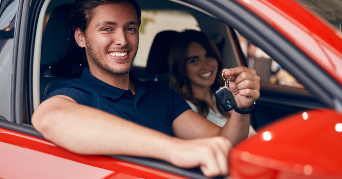 Image of young expats couple driving their new car