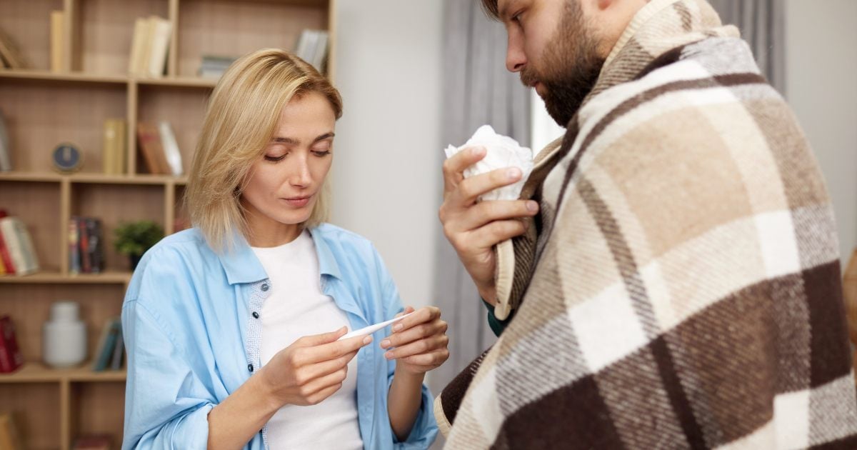 Image of a woman testing her partner's temperature