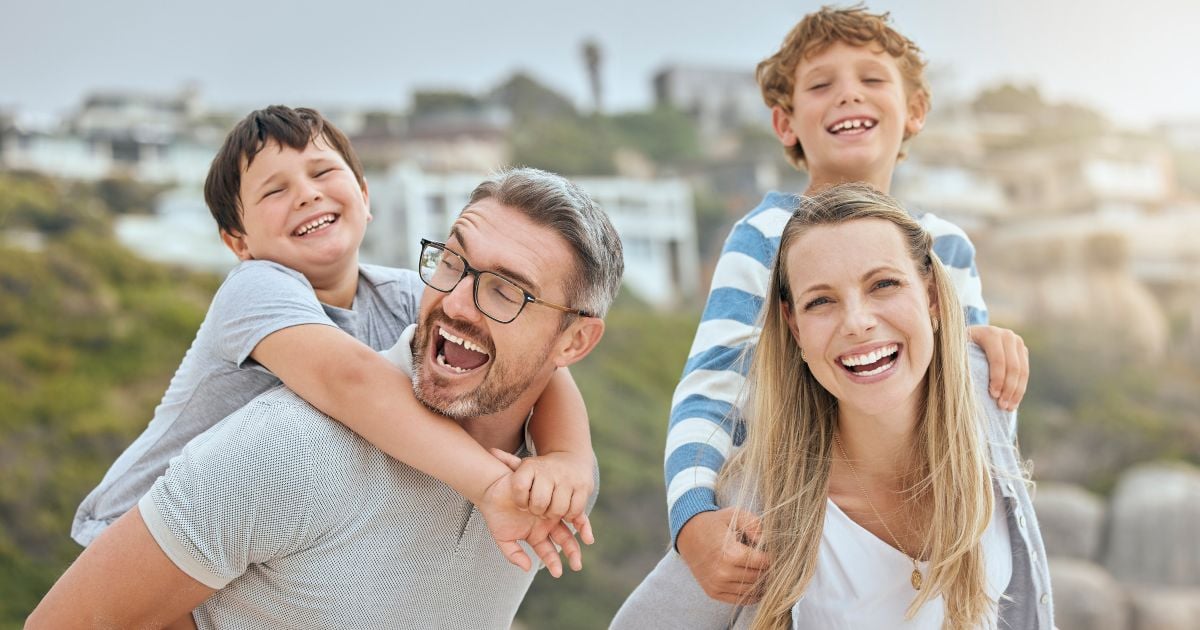 Image of parents children and piggy back at beach with portrait smile or bonding with love on vacation in summer father mother and kids on holiday for connection embrace or together for laugh in sunshine