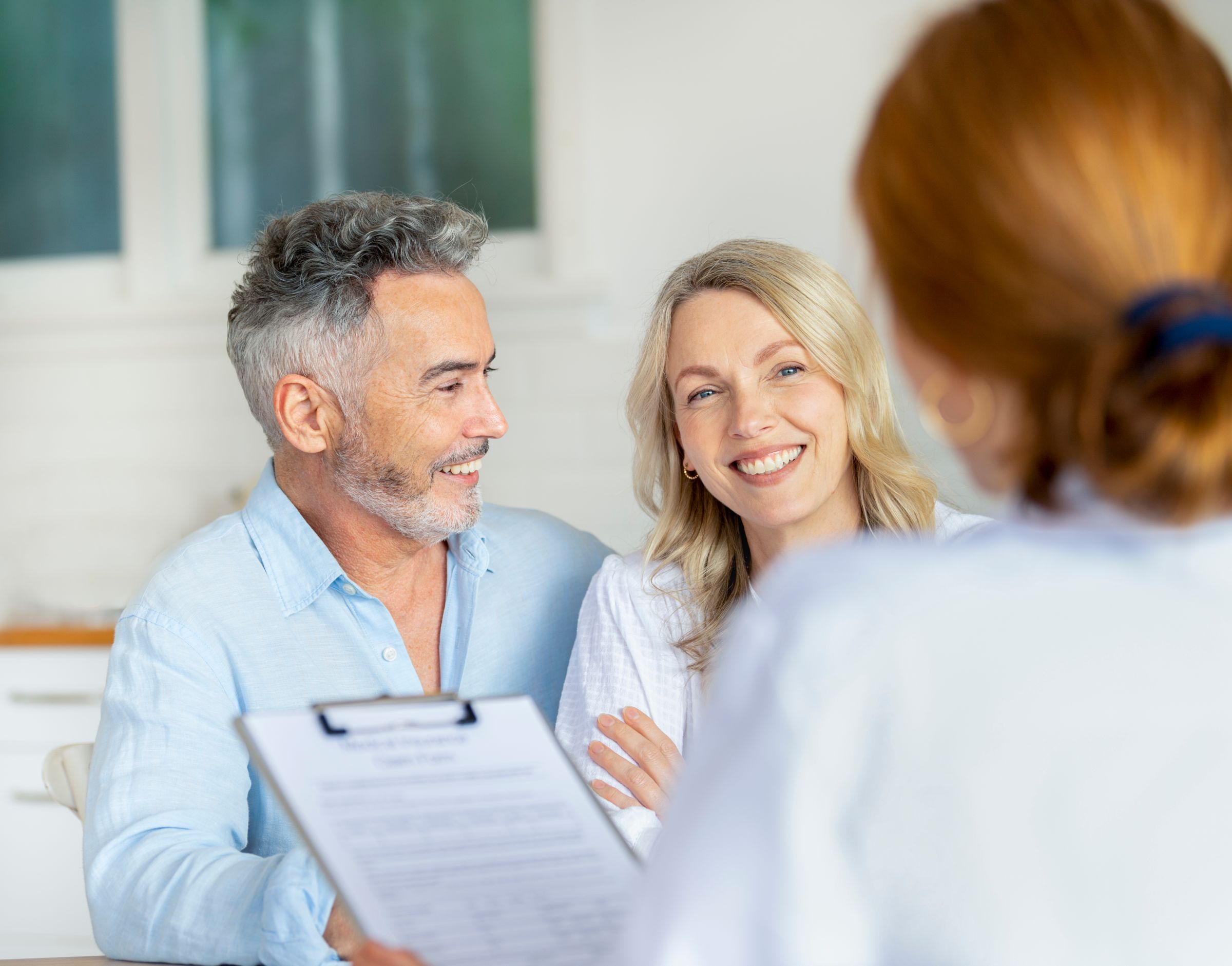 Image of a man looking at his partner in awe as the doctor shares good news